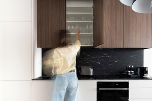 A person reaching into a kitchen cabinet. - Premium Apartments with Parking (Gdańsk)