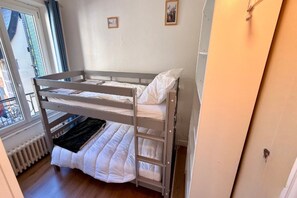 A bunk bed with a lower bunk, a window with a view, and a radiator. - Mont-Dore Apartment for 8 Guests (Mont-Dore)
