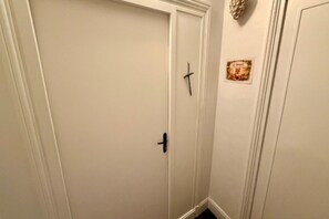 A closed door with a simple black handle, a small decorative item on the wall, and a framed picture. - Mont-Dore Apartment for 8 Guests (Mont-Dore)