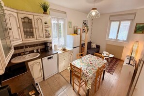 A compact kitchen with a dining area, a refrigerator, and a coffee machine. - Family Apartment in Mont-Dore (Mont-Dore)
