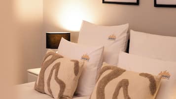 A neatly made bed with white bedding and two decorative pillows with a brown pattern.