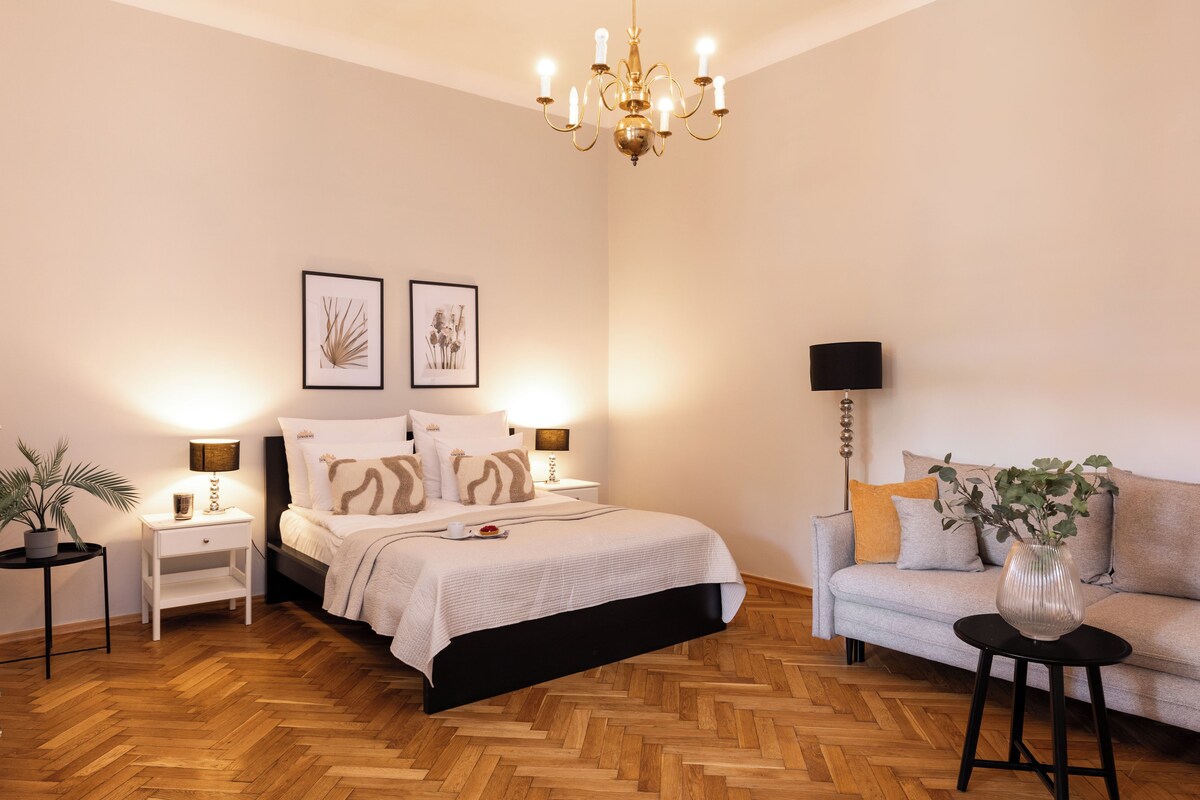 Un dormitorio con cama, mesitas de noche, sofá, lámpara de pie y candelabro.