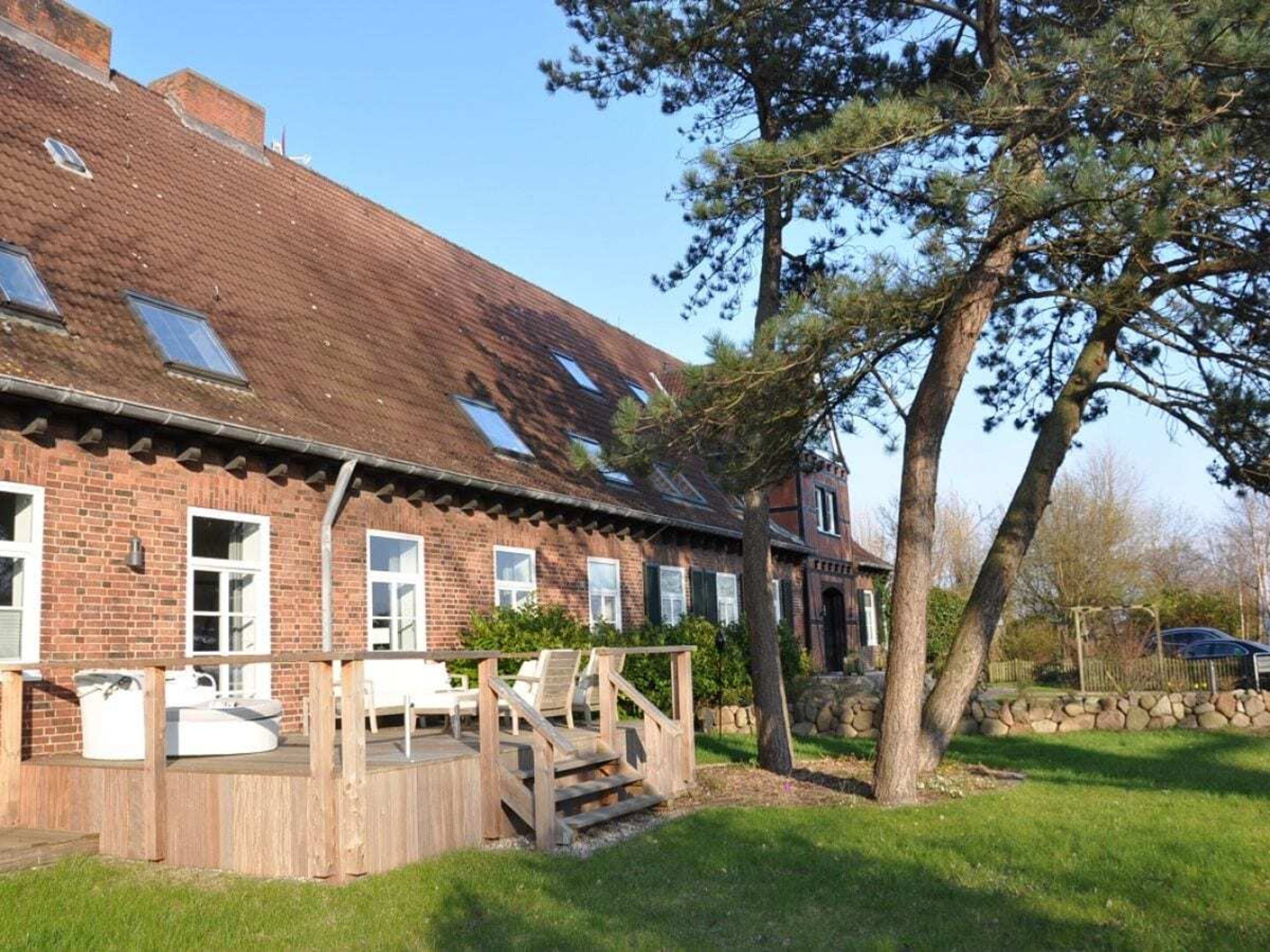 A brick house with a wooden deck, outdoor seating, and a stone wall.