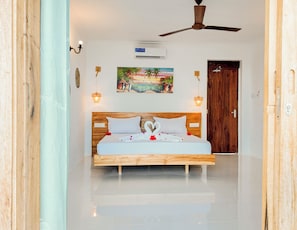 A bedroom with a bed, a ceiling fan, an air conditioning unit, and a painting on the wall. - Amani Bahari (Marumbi)