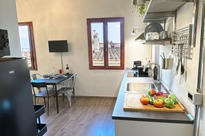 A compact kitchen with a dining area, a large window, and a flat-screen TV. - Otomo Flat-Steps from SMN Station&Airport tram (Florence)