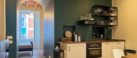 Una cocina moderna con horno empotrado, un lavamanos y una zona de comedor con una silla.