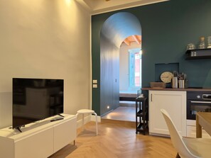 Ein modernes Wohnzimmer mit einem Flachbildfernseher, einem weißen Sofa und einem kleinen Tisch.