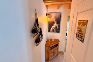 A hallway with a wooden cabinet, a framed picture on the wall, and a poster on the door. - Apartment with Mezzanine, Mont-Dore (Mont-Dore)