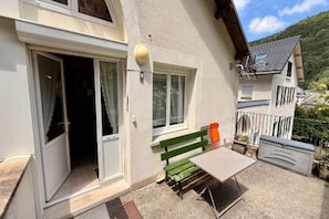 A residential building with a patio area, a green bench, a table, and a door leading to an interior space. - Apartment with Mezzanine, Mont-Dore (Mont-Dore)