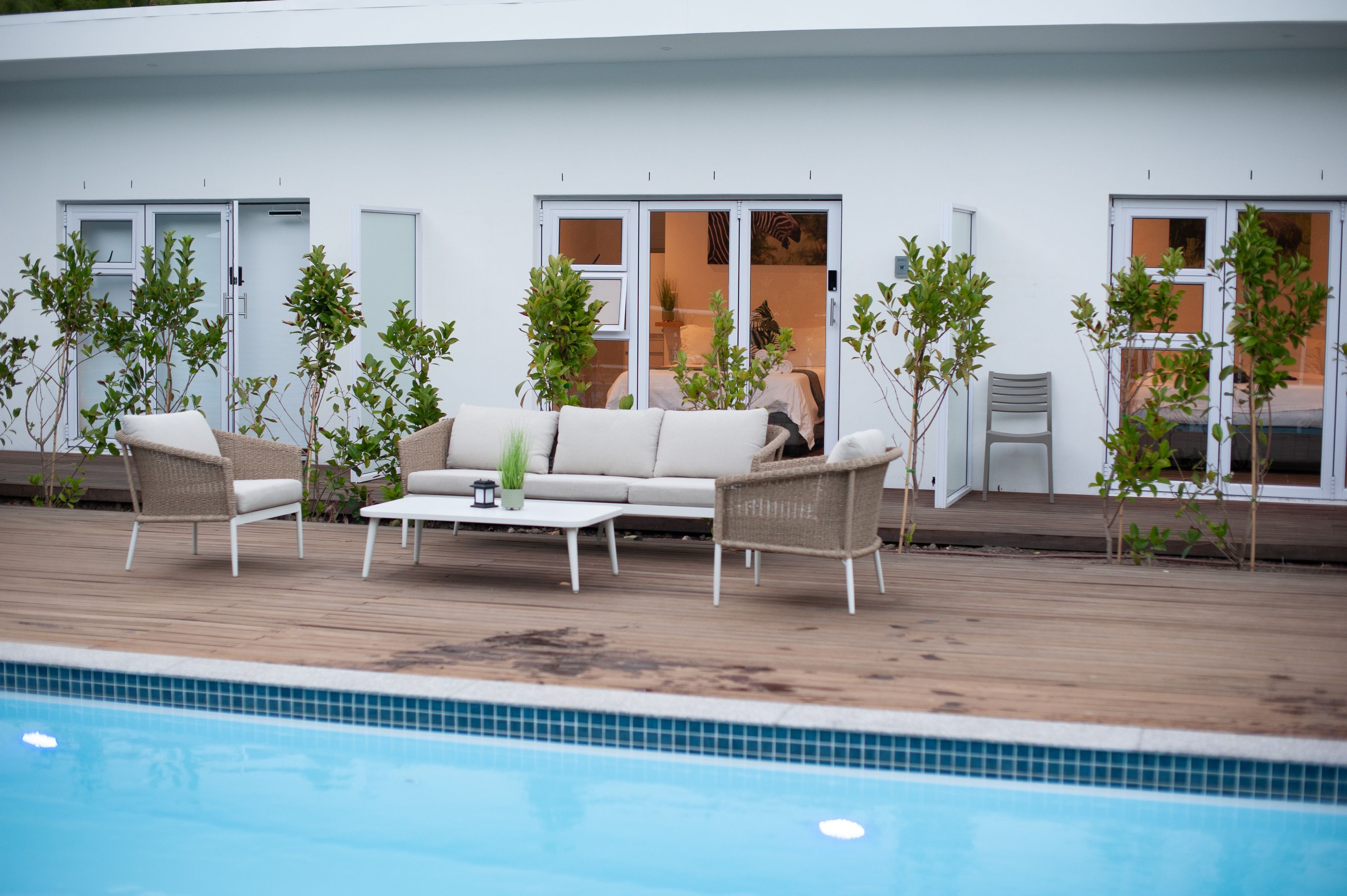 Een zwembadterras met een bank, stoelen en potplanten.