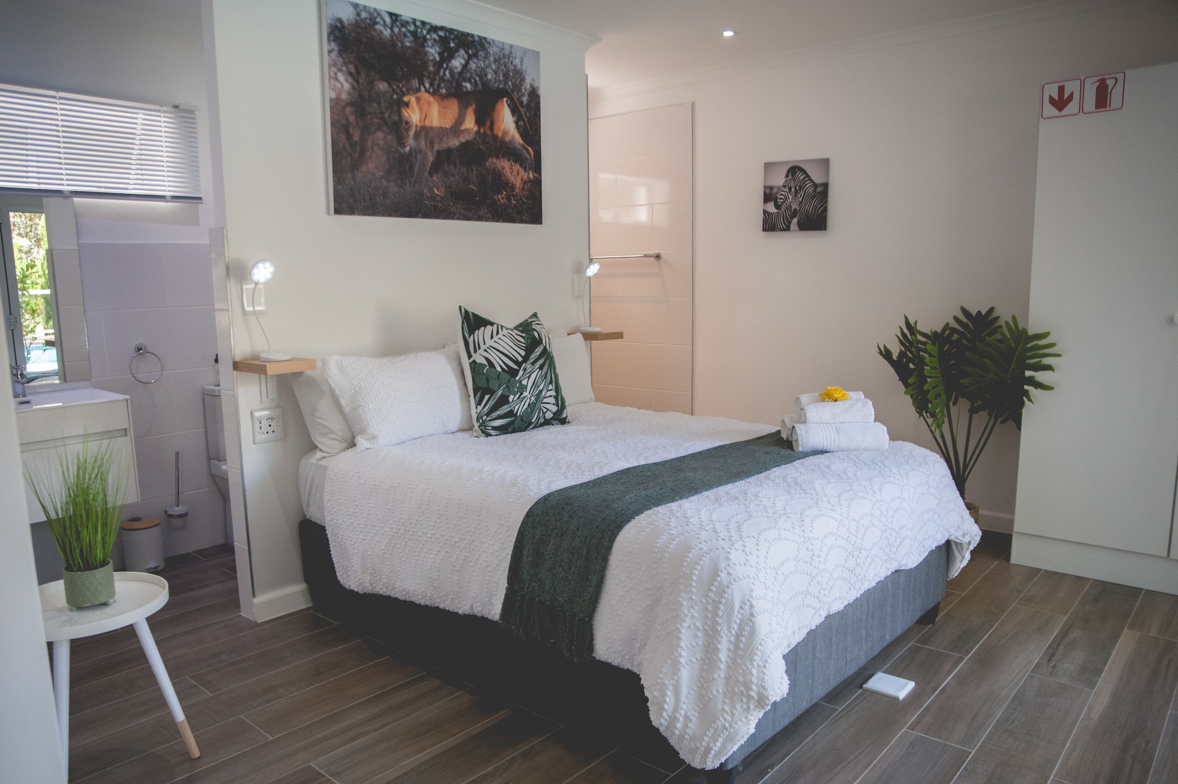 Een moderne slaapkamer met een bed, bureau, spiegel en deur.