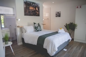 Een moderne slaapkamer met een bed, bureau, spiegel en deur.
