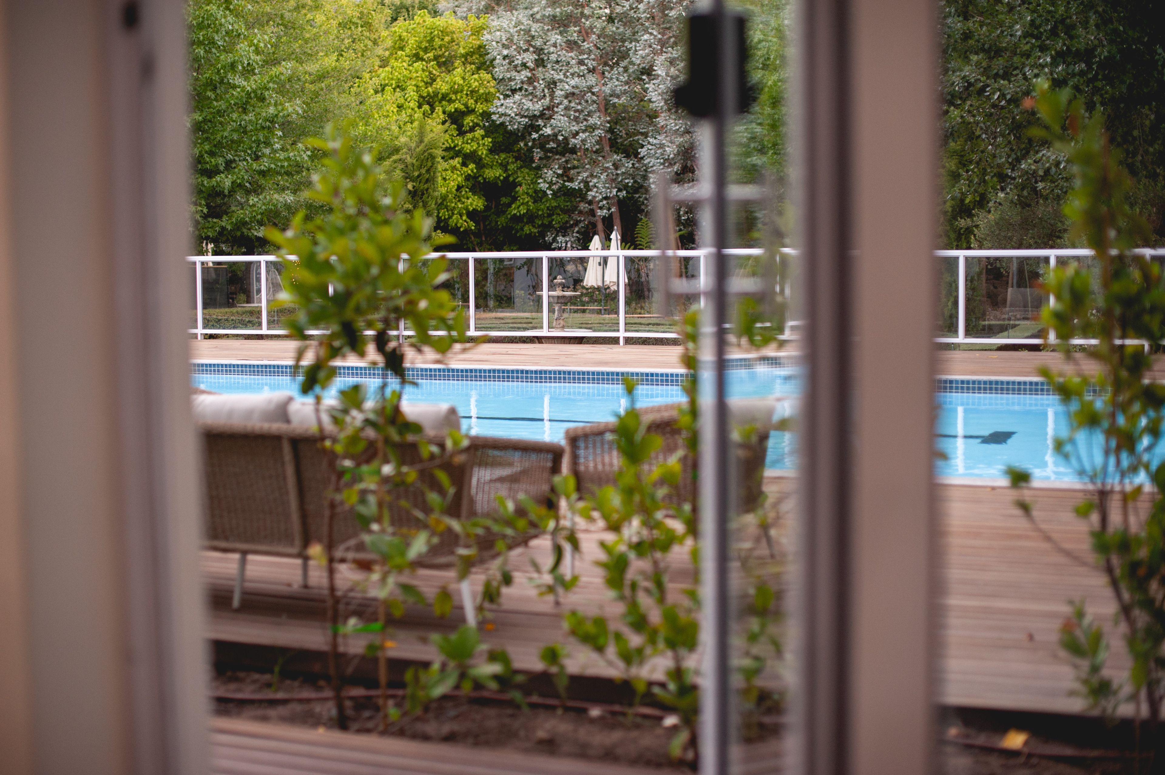 A pool area with a wooden deck, lounge chairs, and a view of the surrounding greenery.