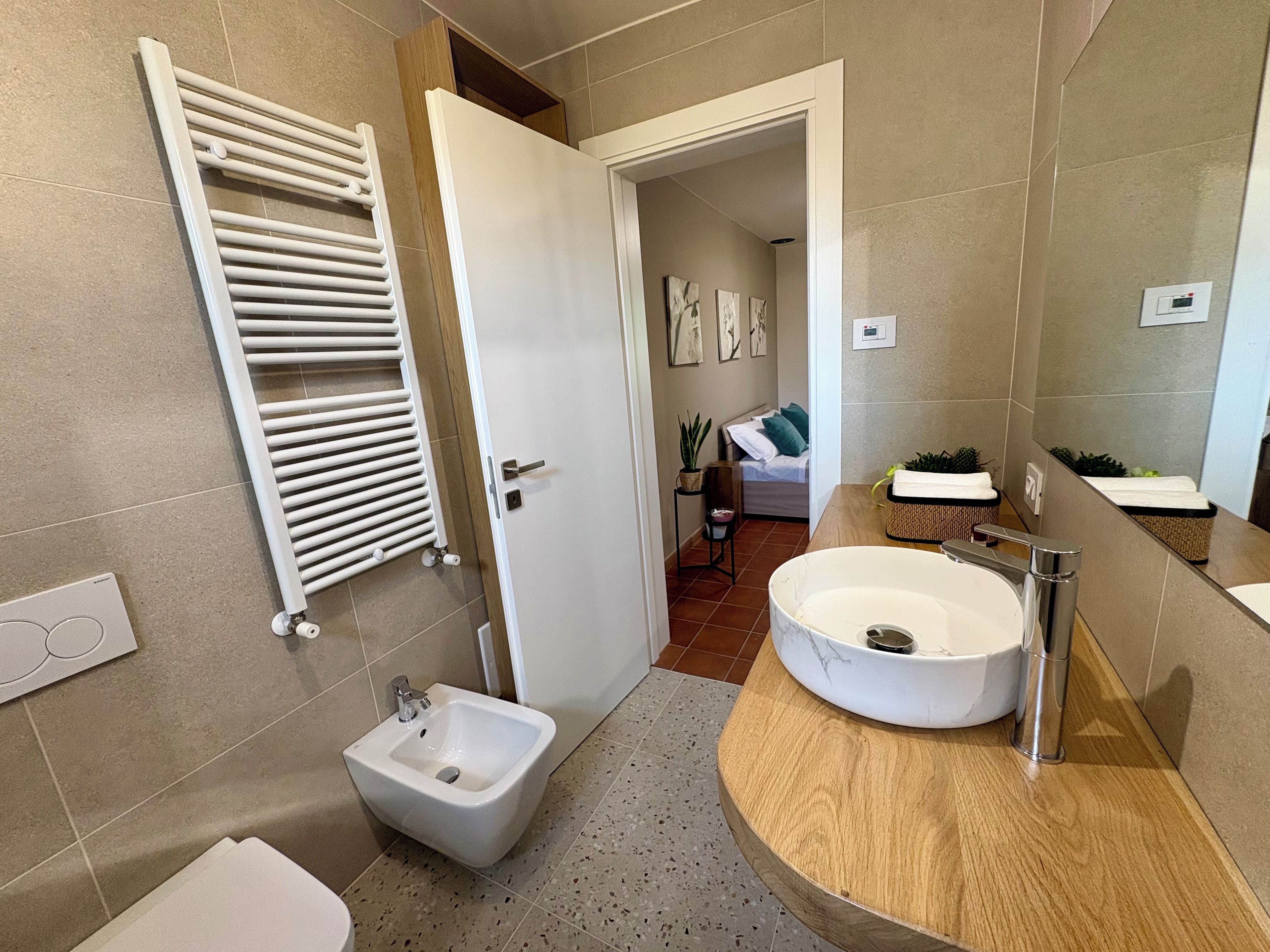 A modern bathroom with a freestanding bidet, a large sink, and a towel rack.