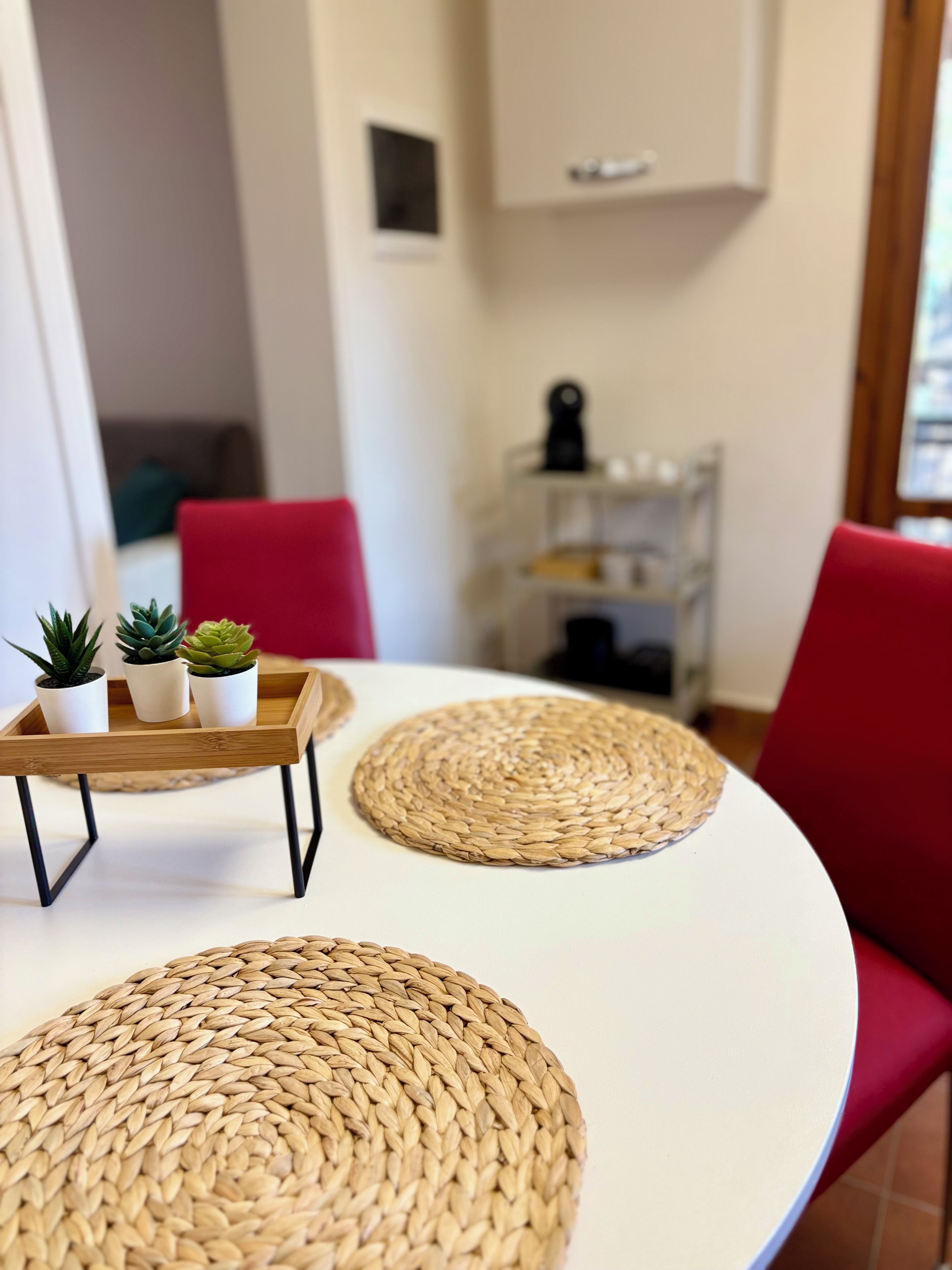 A dining area with a white table, red chairs, and woven placemats.