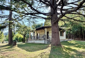 Una casa con un portico, circondata da alberi.