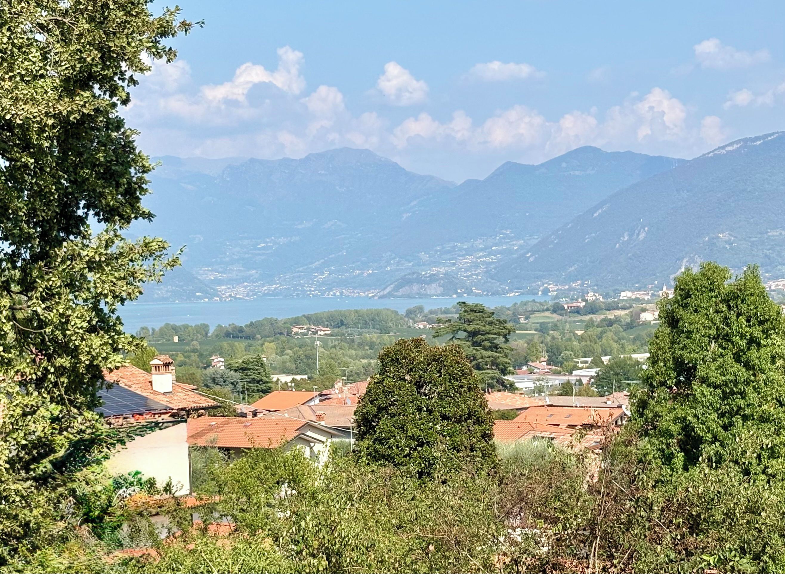 A mountainous landscape with a town in the valley, featuring terraced houses with red roofs and lush greenery.
