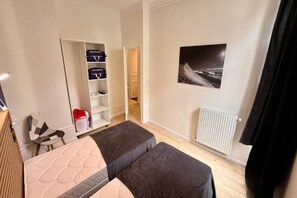 A bedroom with a bed, a wardrobe, a radiator, and a framed picture on the wall. - Apartment near Parc Fenestre (La Bourboule)