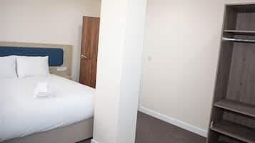 A hotel room with a bed, a wooden wardrobe, and a white pillar.
