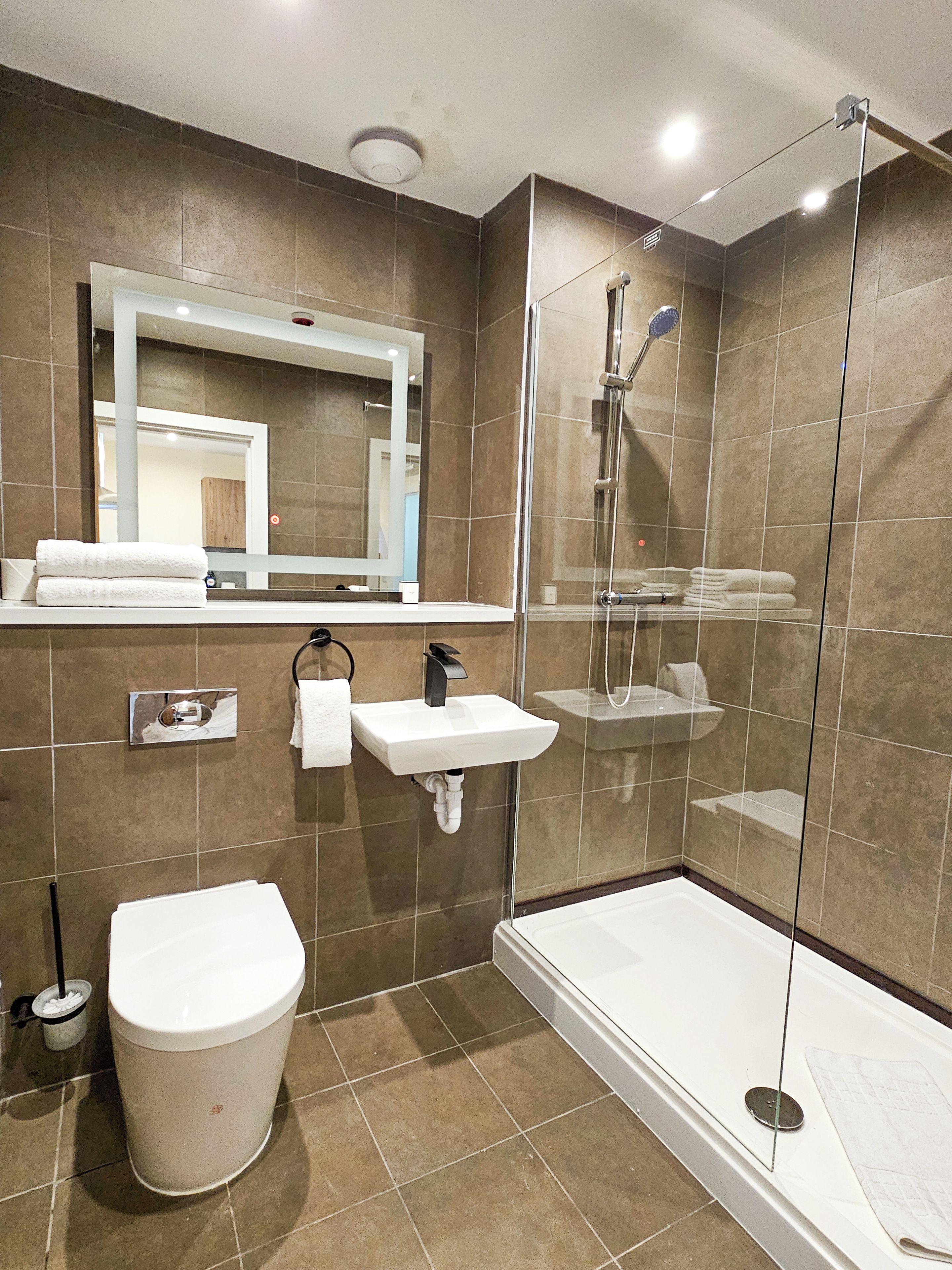 A modern bathroom with a glass-enclosed shower, a white sink, and a toilet.