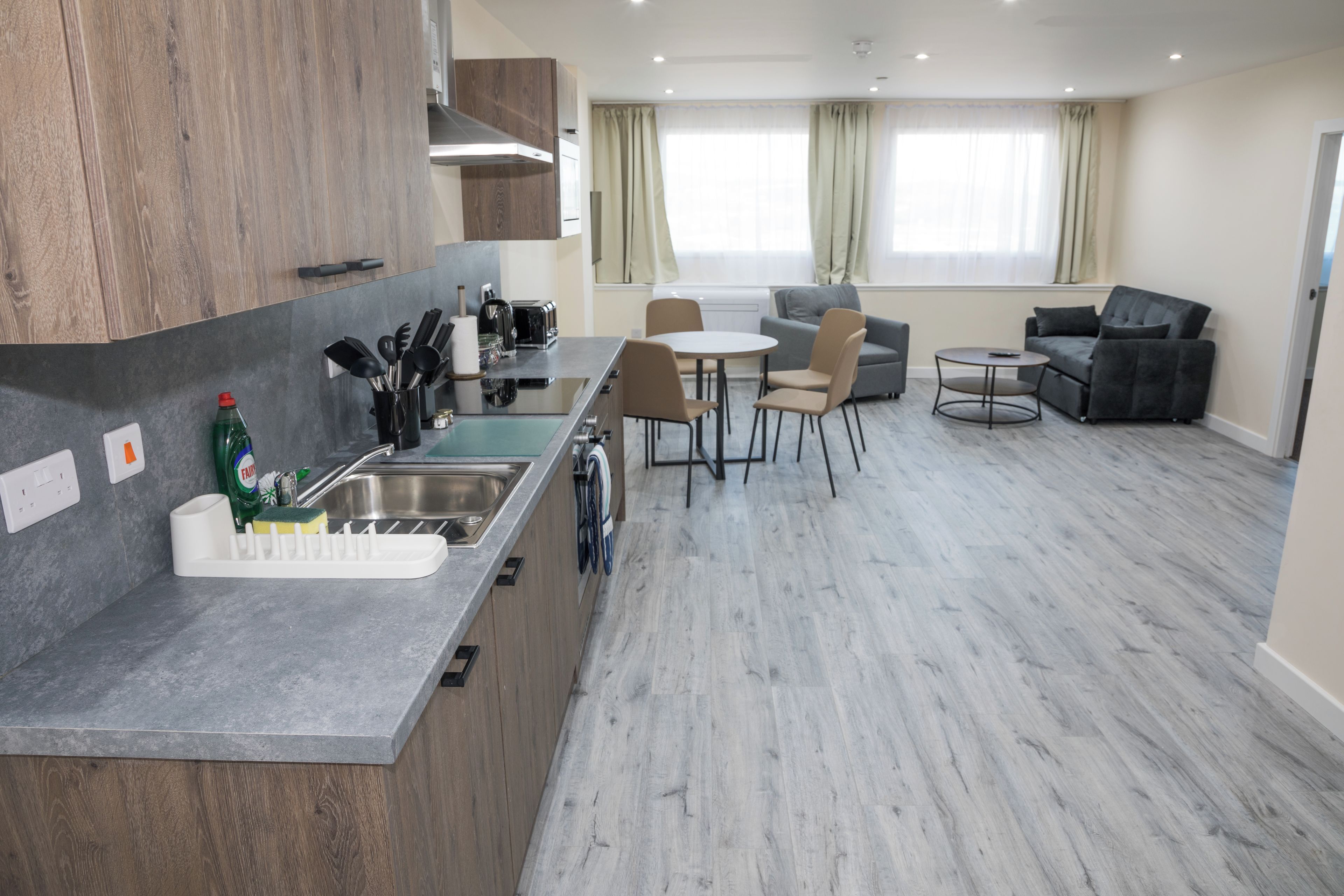 A modern kitchen with a built-in stove, a sink, and a dining area with a table and chairs.