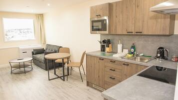 A compact kitchen with wooden cabinets, a built-in microwave, a sink, and a dining area with a table and chairs.