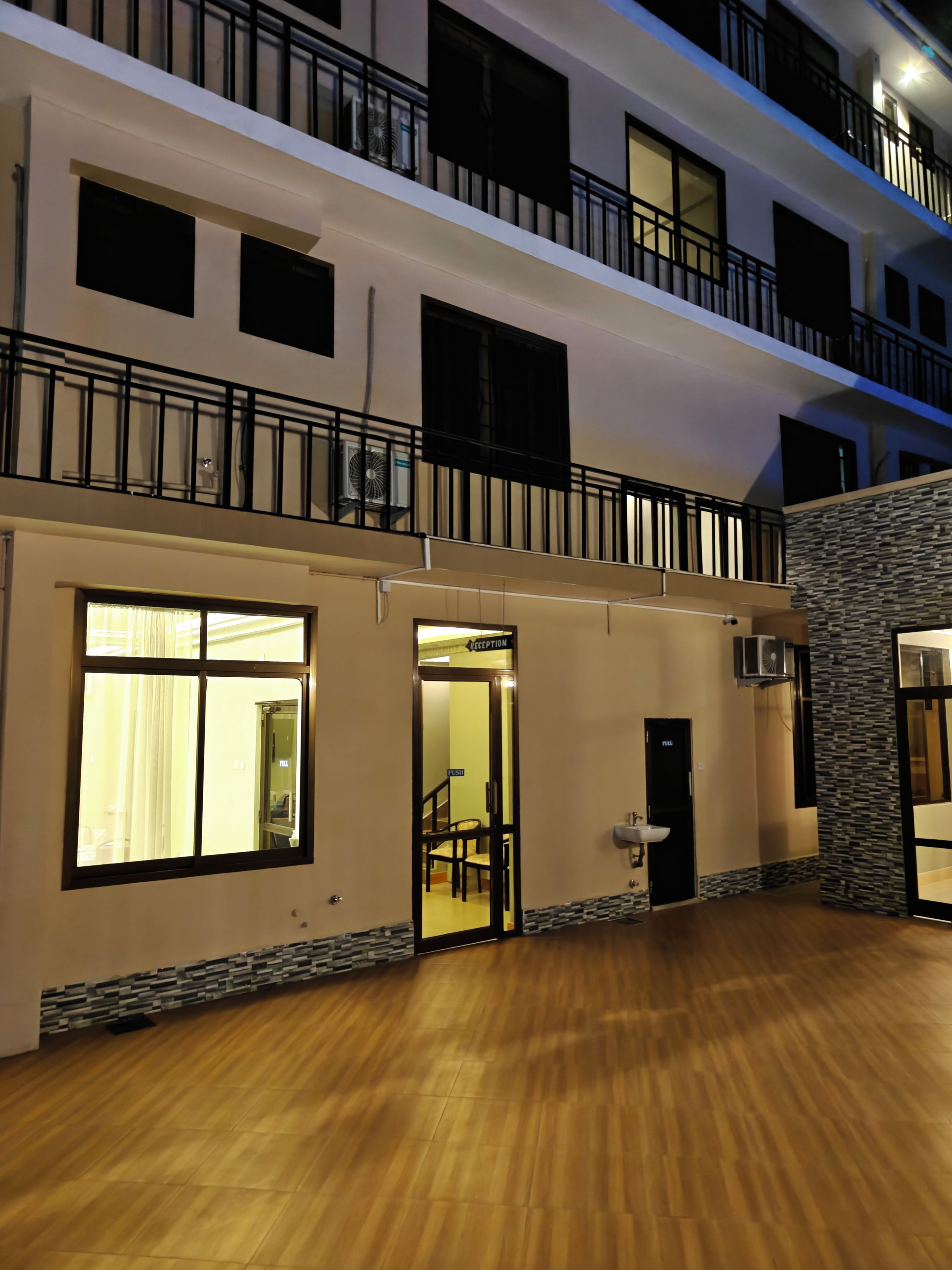 A multi-story hotel with a reception area, a staircase, and a balcony.