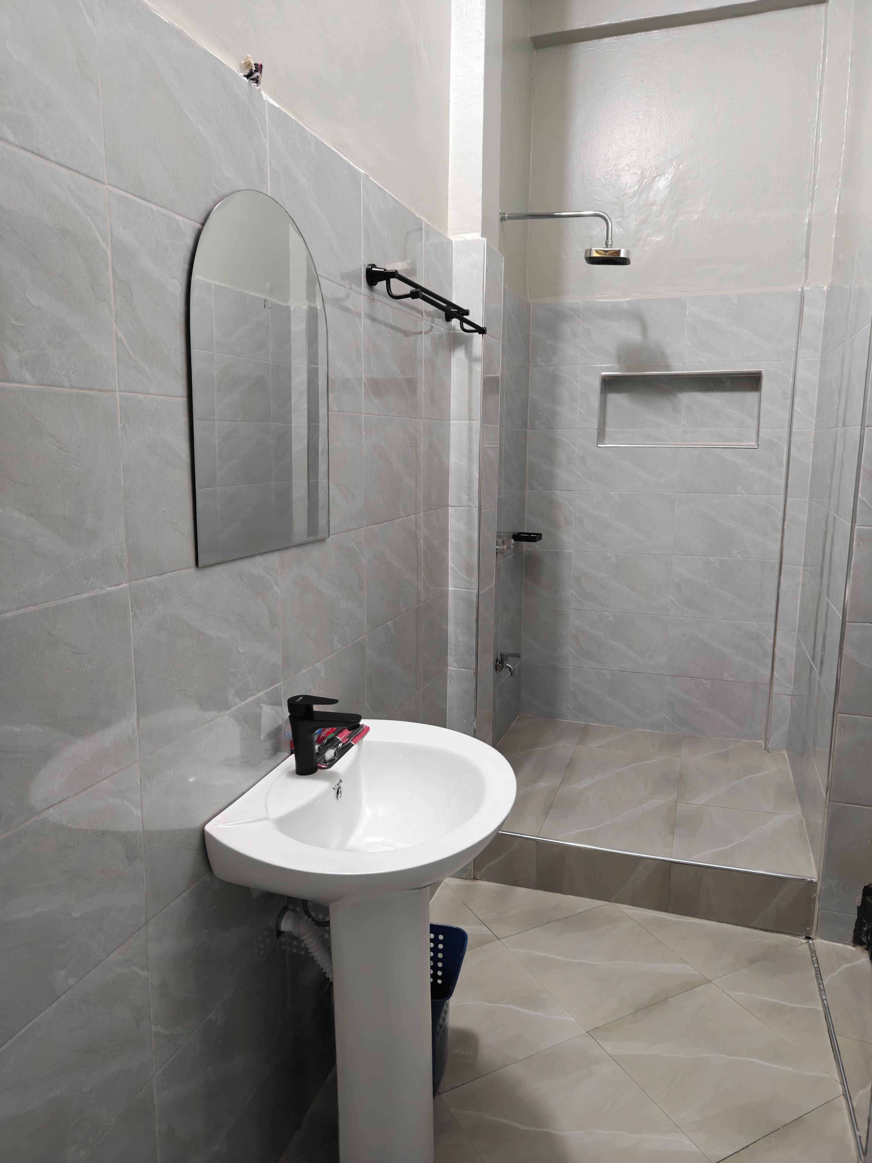 A bathroom with a white sink, a mirror, and a shower area.