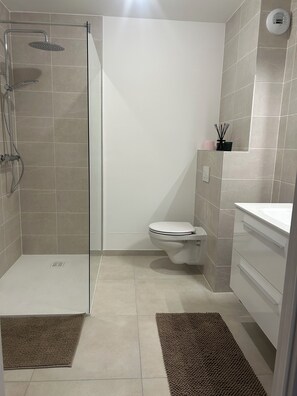 Une salle de bain moderne avec une douche à parois de verre, des toilettes et un lavabo.