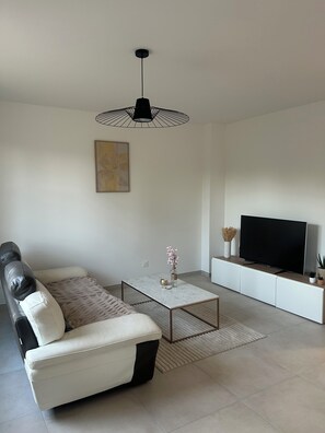 Una sala de estar moderna con sofá, mesa de centro, televisor y objetos decorativos.