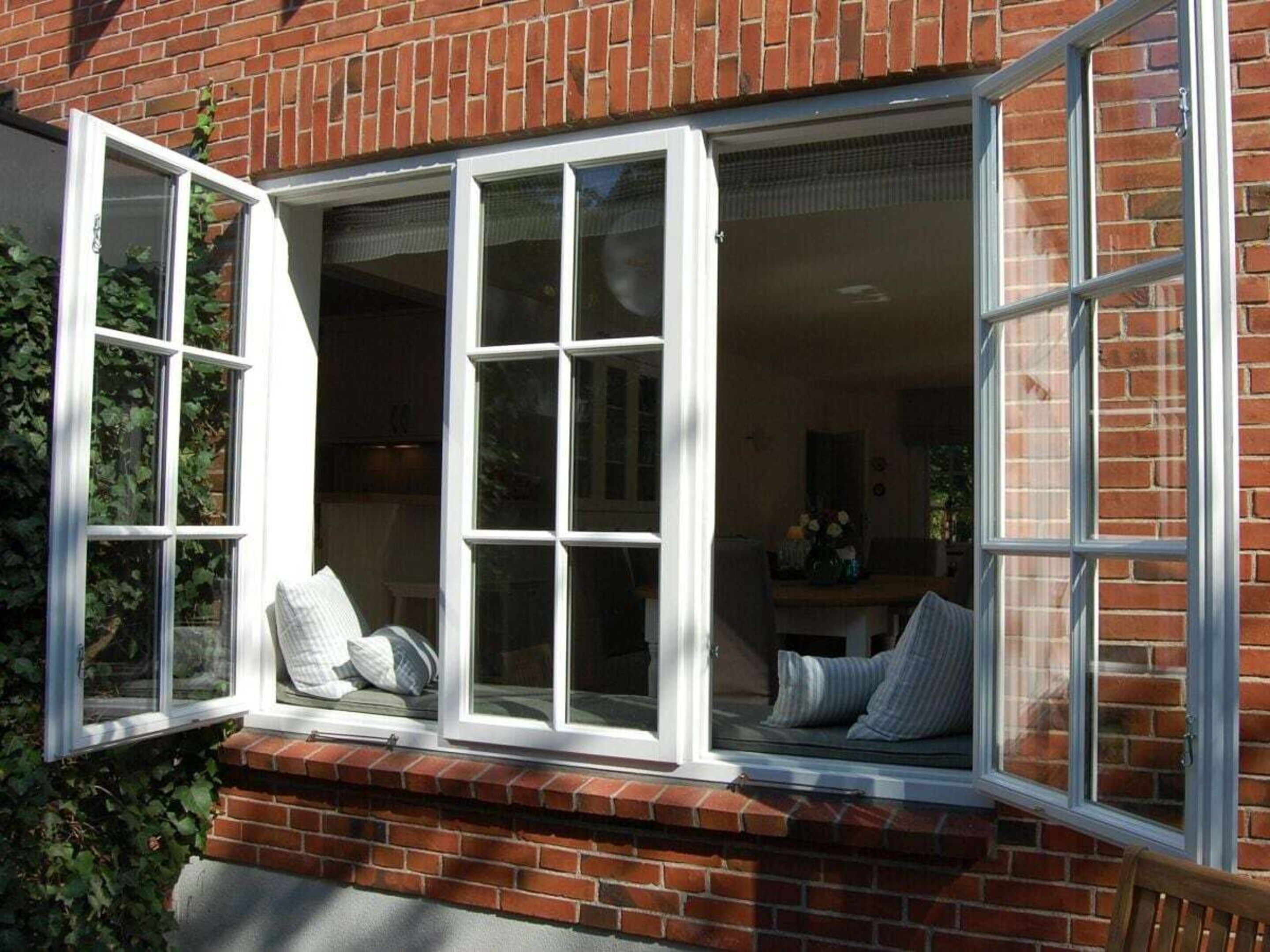 A bay window with multiple panes, a brick exterior, and a bench with cushions.