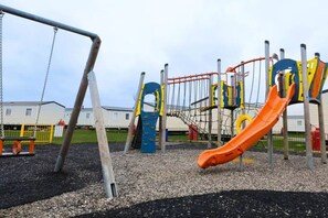 Un'area giochi con uno scivolo, altalene e strutture per arrampicarsi.