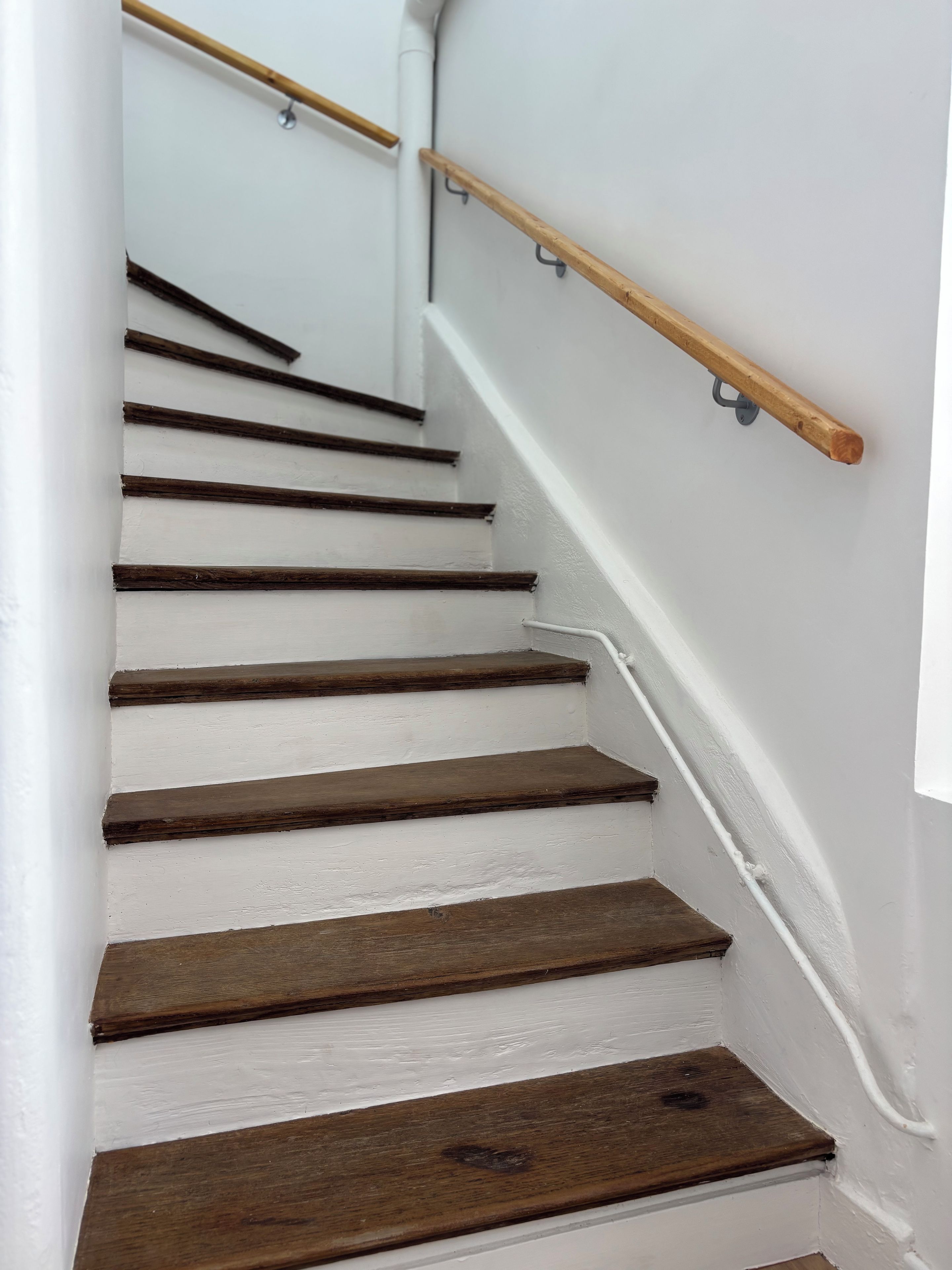 Un escalier avec des marches en bois et une rampe blanche.