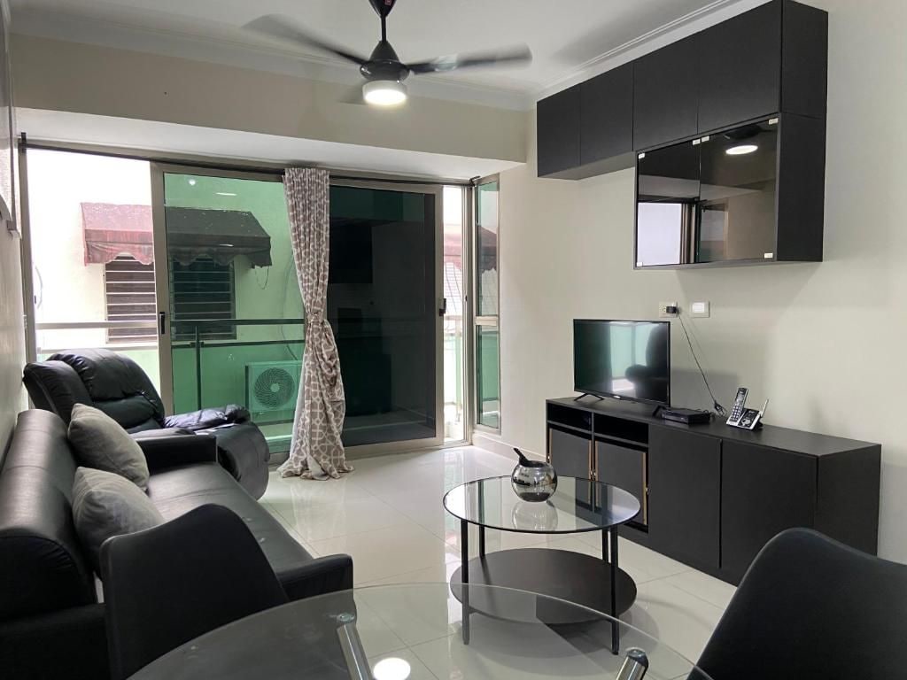 A modern living room with a sofa, a glass coffee table, a television, and a ceiling fan.