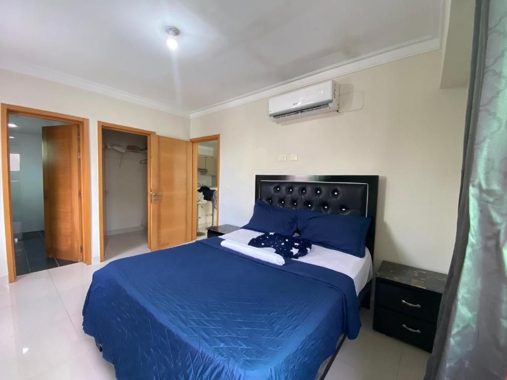 A bedroom with a bed, a wardrobe, and an air conditioning unit.