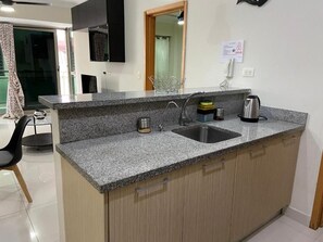 Eine Küche mit Granit-Arbeitsplatten, einer Edelstahl-Spüle und Holzschränken.