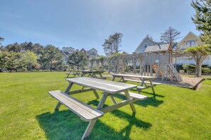 Spacious green lawn with picnic tables and playground in a quiet coastal neighborhood, framed by trees and charming homes. - Spacious Olivia Beach Home: Hot Tub, Pool, Games & Pet Friendly! Sleep 10 (Lincoln City)