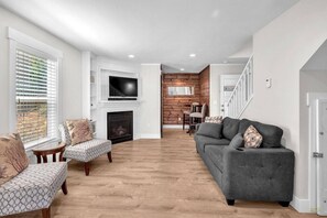 Ein Wohnzimmer mit Kamin, einer Couch, einem Sessel und einem Fernseher.