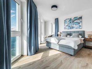A modern bedroom with a large bed, a view of the sea, and a ceiling light. - Apartment in Olpenitz With Swimming Pool (Kappeln)