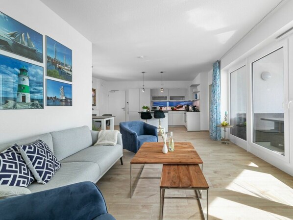 A modern living room with a sofa, a coffee table, and a dining area in the background. - Apartment in Olpenitz With Swimming Pool (Kappeln)