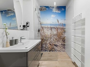 A modern bathroom with a beach mural, a sink with a vase, and a radiator. - Apartment in Olpenitz With Swimming Pool (Kappeln)