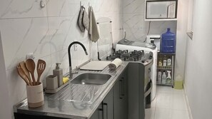 Eine moderne Küche mit Spüle aus Edelstahl, einem Gasherd und einer Mikrowelle.