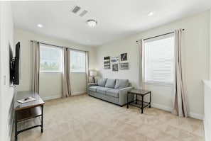 A living room with a sofa, a coffee table, a TV, and a lamp. - 5-bedroom house with pool and spa near Disney (Kissimmee)
