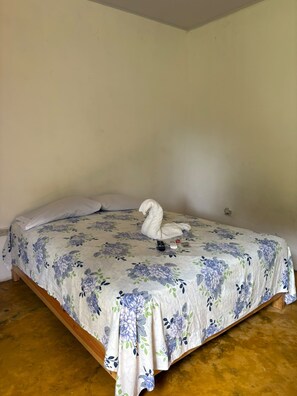 Una cama individual con una colcha estampada con flores y una toalla con forma de cisne.