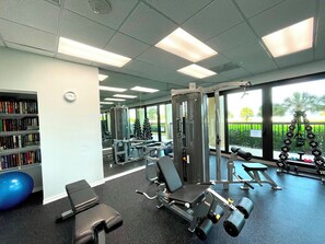 Ein Fitnessraum mit Trainingsgeräten, einem blauen Gymnastikball und einem Bücherregal.