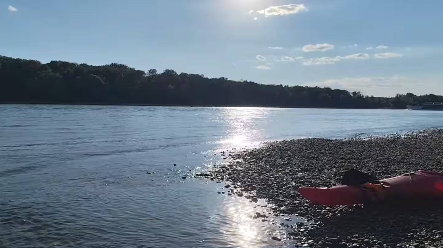 Een rustig wateroppervlak met een heldere lucht en een verre kustlijn.