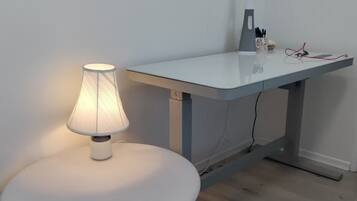 Ein moderner Arbeitsplatz mit einem runden weißen Tisch, einem Schreibtisch mit einer Lampe und einem kleinen Teppich.