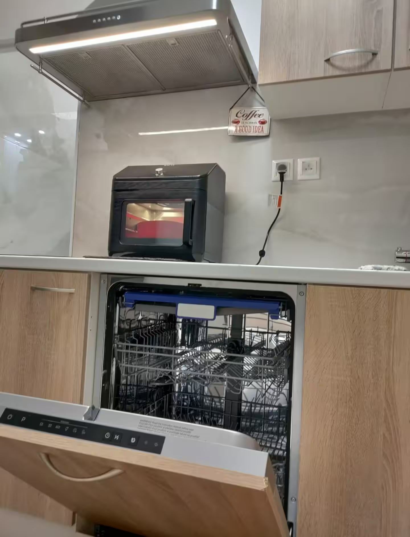 Een keuken met een inbouwvaatwasser, een magnetron en een bord met opschrift 'koffie' aan de muur.