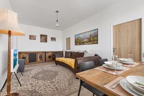 A living room with a sofa, a dining table set for two, and a fireplace.