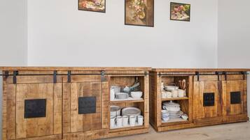 Ein Holzschrank mit Metallhaken, der Teller, Schüsseln und Tassen beherbergt.